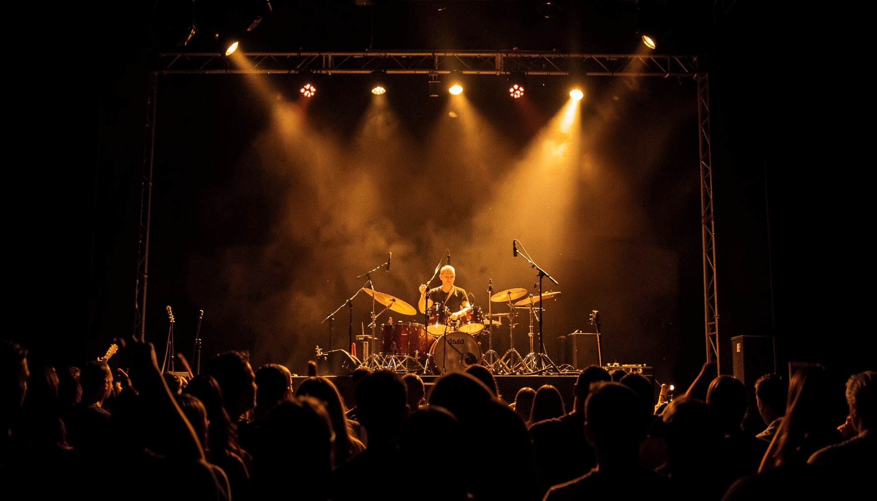 A live music performance with dramatic stage lighting in deep amber and shadow